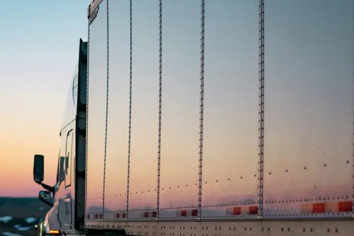 Camión con contenedor refrigerado en ruta al atardecer