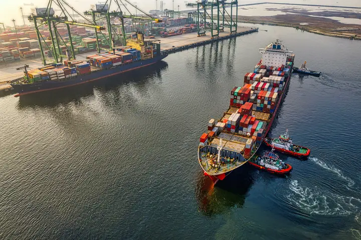 Portacontenedores zarpando del puerto con remolcadores